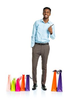 Happy african american man with shopping bags and holding credit card on white background. Holidays concept