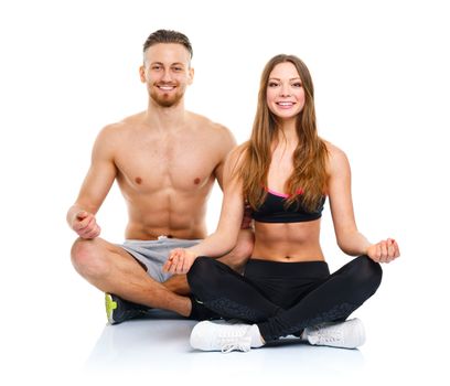 Sport couple - man and woman after fitness exercise sitting with dumbbells on the white background