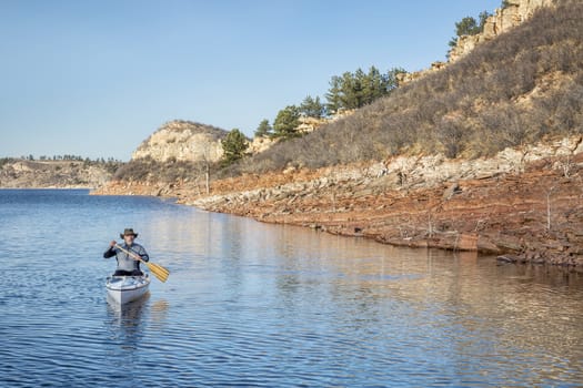 senior male paddling a decked expedition canoe on a mountain lake - Horsetooth Reservoir near Fort Collins, Colorado, early spring scenery