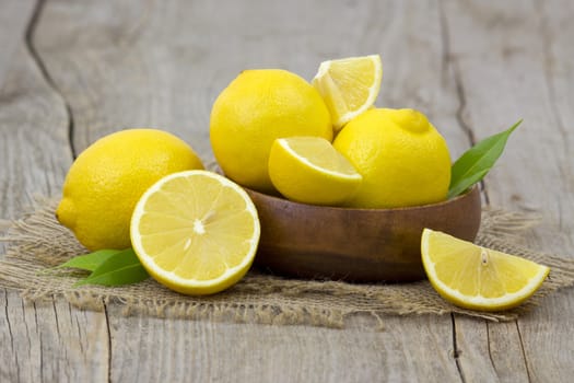 fresh lemons in a bowl on wooden background