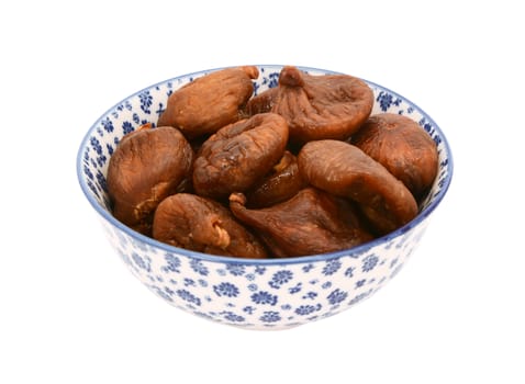 Whole dried figs in a blue and white porcelain bowl with a floral design, isolated on a white background