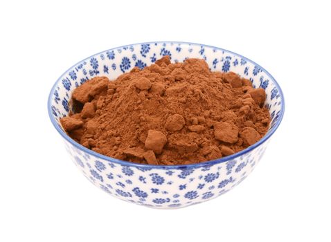 Cocoa powder in a blue and white porcelain bowl with a floral design, isolated on a white background