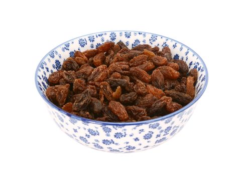 Sultanas in a blue and white porcelain bowl with a floral design, isolated on a white background