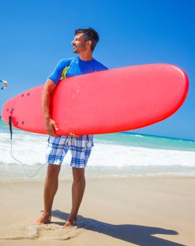 Strong young surf man at the beach with a surfboard.