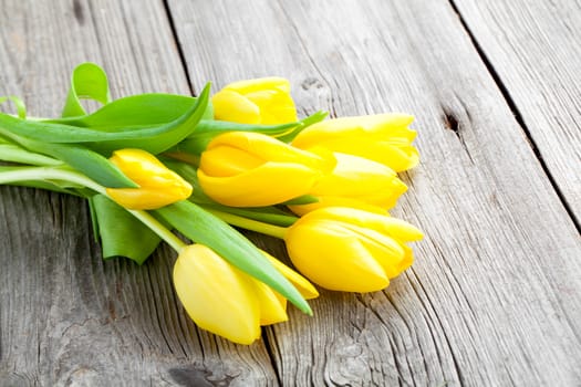 Bouquet of yellow tulips on old wooden boards