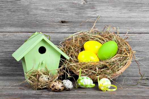 easter decoration with eggs, birdhouse. wooden background