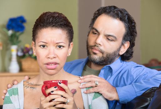 Worried hispanic couple sitting together with coffee