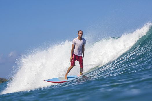 Surfer on Amazing Blue Wave, Bali island.