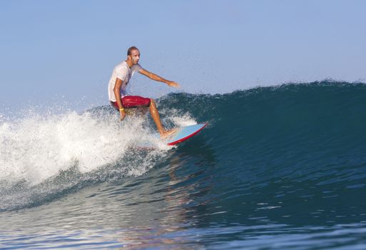 Surfer on Amazing Blue Wave, Bali island.