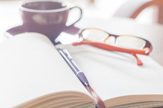 Pen, notebook coffee cup and eyeglasses on the wooden table, stock photo