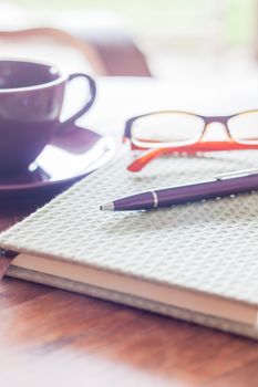 Pen and green covered notebook on wooden table, stock photo