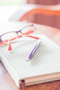 Pen and eyeglasses on notebook, stock photo