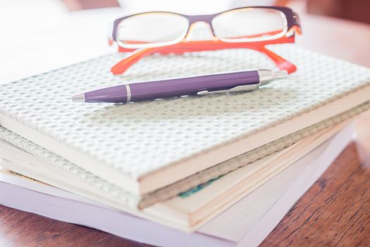 Pen and eyeglasses on three notebooks, stock photo