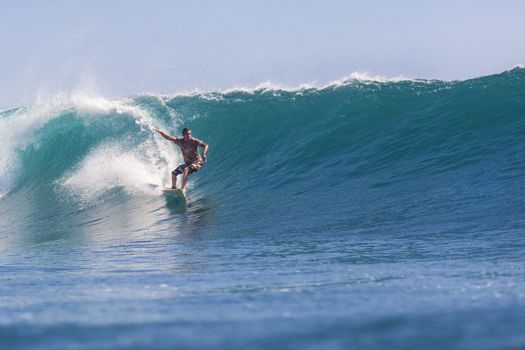 Surfer on Amazing Blue Wave, Bali island.