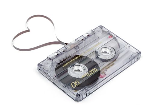 Audio cassette tape isolated on white backgound. Film shaping heart, Valentine postcard. Label text love songs.