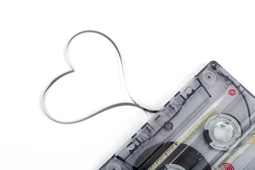 Audio cassette tape isolated on white backgound. Film shaping heart, Valentine postcard. Label text love songs.