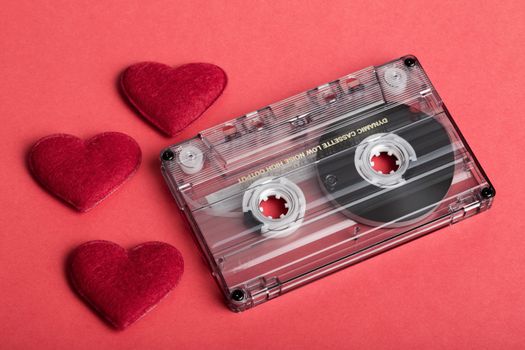 Audio cassette tape on red backgound with fabric heart, Valentine postcard. Love concept.