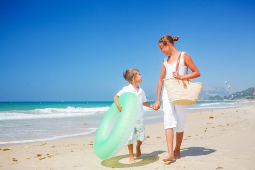 Beautiful brother and sister walk on the beach