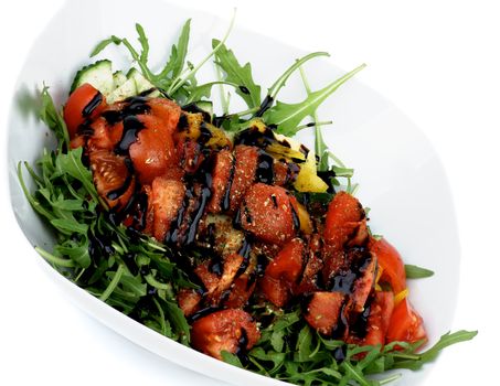 Vegetable Salad with Slices of Cucumber and Yellow Bell Pepper, Leafy Arugula, Wedges of Cherry Tomatoes, Balsamic Sauce and Spices in White Bowl closeup