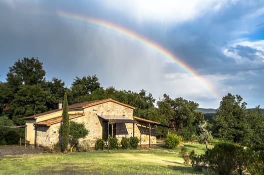 Rural cottage in Tuscany, italy, after a rainstorm, rainbow in the sky