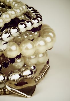 Stack of Various Pearl, Silver and Black Jewelry Gems Bracelets with Silver Heart Shape closeup. Retro Styled