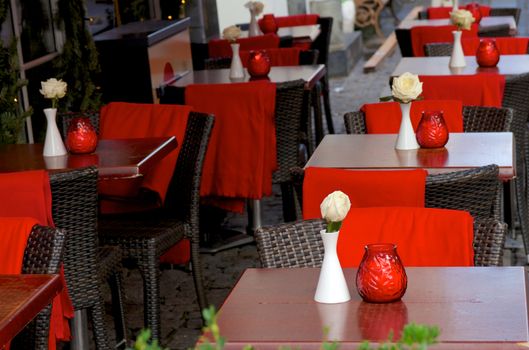 Romantic Street Cafe with White Roses, Candles and Red Plaids on Wicker Chairs Outdoors