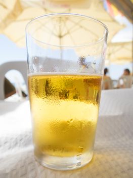 macro of short crystal glass full of lager beer typical spanish drink on white paper tablecloth restaurant