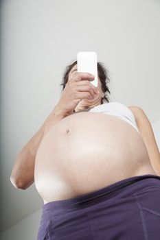 pregnant woman purple trousers bare belly watching smartphone