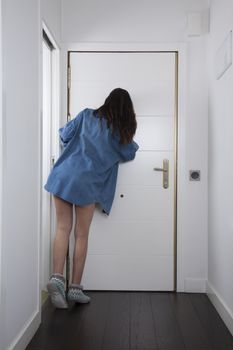 blue jeans shirt woman back looking to peephole interior house hall white door brown wooden floor