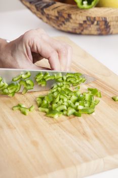 woman hands cutting green fresh pepper pieces on brown wood plank white worktop