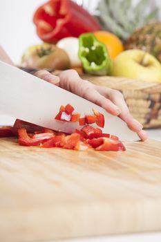 woman hands cutting red fresh pepper slices on brown wood plank white worktop