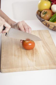 woman hands cutting red fresh tomato slices on brown wood plank white worktop