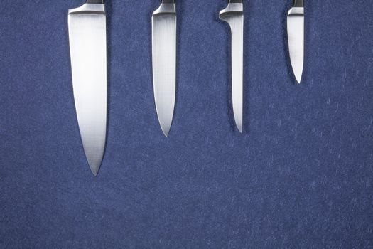 four big kitchen knife bright silver blades on blue background