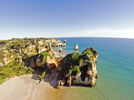 Aerial from rocks and ocean at Praia tres Irmaos in Algarve Portugal