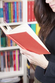 red book in black shirt brunette woman hand over library background