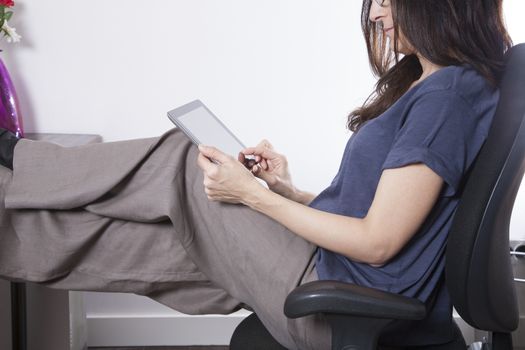 woman blue shirt sitting at black seat in office touching screen tablet