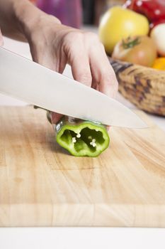 woman hands cutting green fresh pepper slices on brown wood plank white worktop