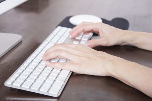 woman hands typing on white keyboard computer brown wooden table