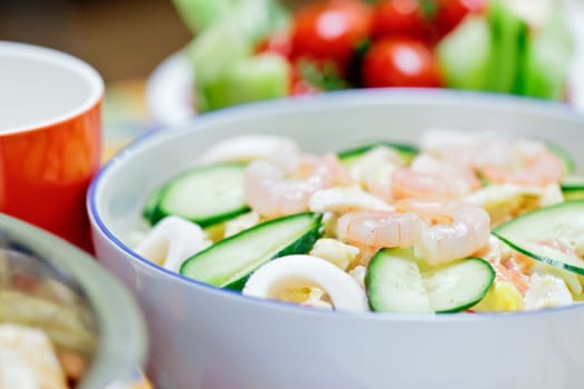 Delicious salad with shrimps, squid and vegetables on a festive table