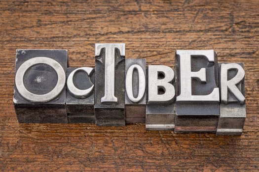 October word in mixed vintage metal type printing blocks over grunge wood