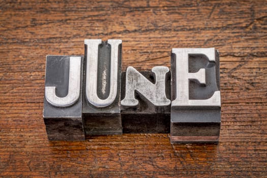 June word in mixed vintage metal type printing blocks over grunge wood