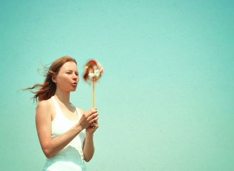 Young woman with a colorful pinwheel, retro styled image, paper texture.