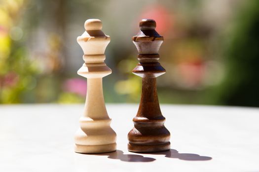 Chess pieces, queens on white table with blurry background.