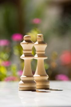 Chess pieces, queens on white table with blurry background.