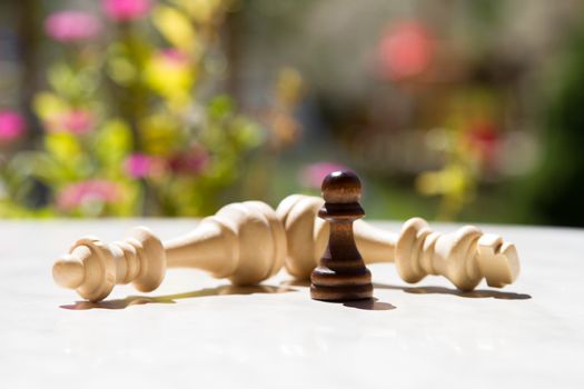 Chess pieces, pawn and queens on white table with blurry background.