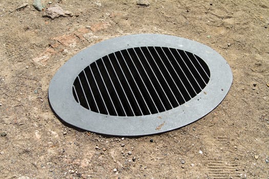 Metal drain water on sand.