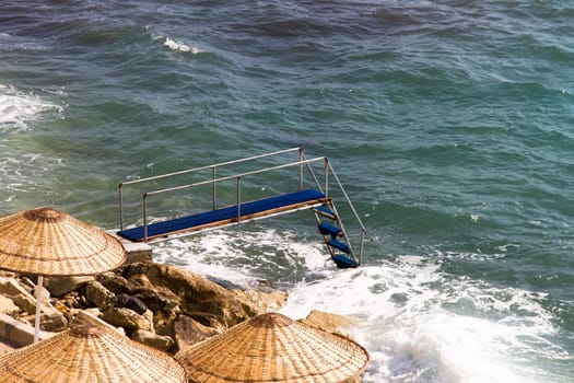 Pier on wavy clean sea.
