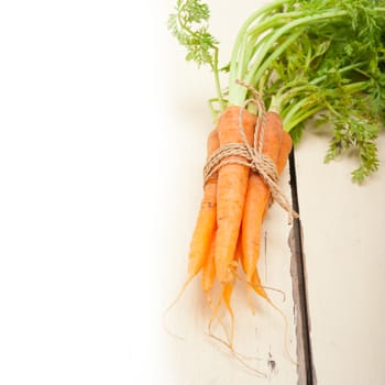 fresh baby carrots bunch tied with rope on a rustic table