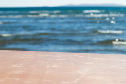 Empty wooden table for your product, wavy sea on blurry background.