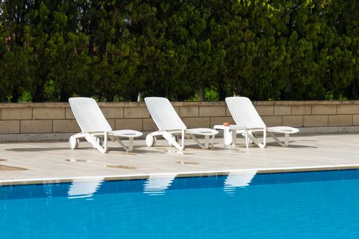 Sunbed near blue clear swimming pool.